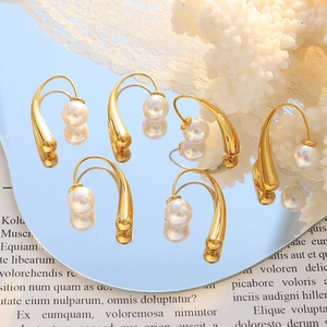 Elegant U-shaped gold earrings with faux pearls displayed on a reflective mirror surface