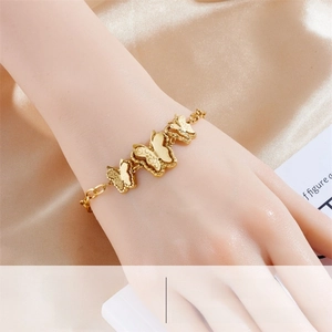 Detail of three golden butterfly charms on a polished stainless steel chain link bracelet