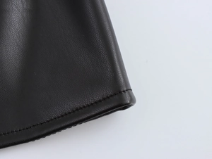 Close-up of the black PU leather fabric texture and stitching details of the mini dress