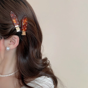 Detailed close-up of tortoise shell acrylic hair clips with colorful rhinestones on a model