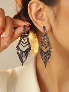 Close-up of elegant long tassel chandelier earrings with sparkling dark gemstones on model
