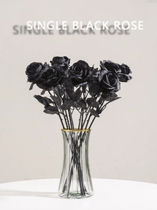 Close-up of artificial black roses in a gold-rimmed glass vase for Gothic home decor