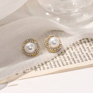 Detailed shot of golden spiral pearl earrings with crystal inlay on elegant white tulle