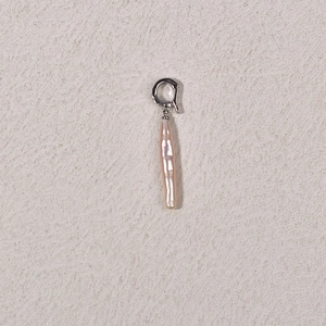 Baroque pearl earring with silver hook on textured beige background in macro view
