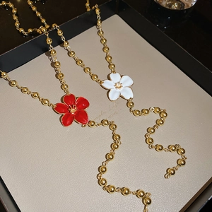 Detail of red and white flower pendants on golden beaded chains in a tray