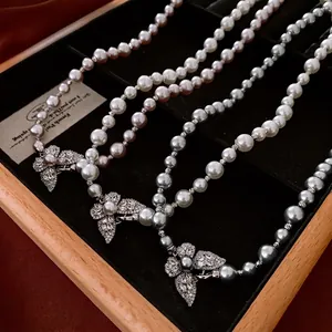 Trois colliers de perles élégants avec fermoirs papillon en zircon sur velours noir