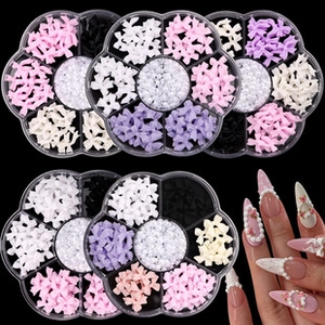 Detailed view of 3D nail art bows and pearls in storage boxes with pink manicure design