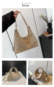 Detail view of khaki nylon hobo bag featuring silver metal butterfly embellishments