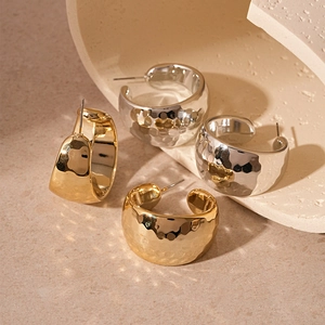 Chunky gold and silver C-shaped hoop earrings with hammered metal texture design