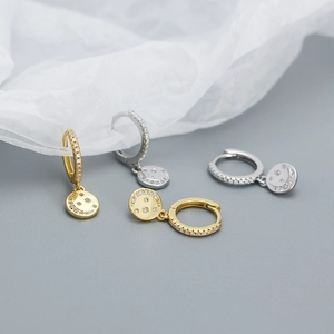 Detail of gold and silver sterling silver hoop earrings with zircon star and moon charms