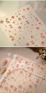 Macro shot of 3D embossed nail stickers featuring red flowers and gold bow details