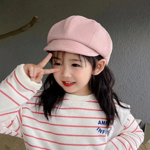 Pink girl's octagonal beret hat styled with a striped sweatshirt in an outdoor setting