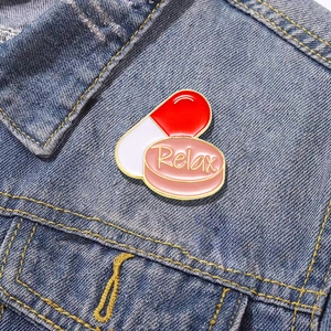 Cartoon capsule and pill enamel brooch with Relax engraving on blue denim jacket