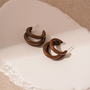 Détail de boucles d'oreilles C à trois couches marron café sur socle en pierre