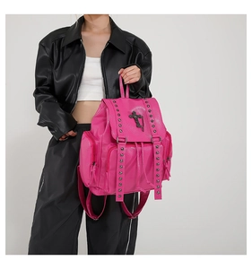 Close-up of pink leather backpack featuring silver rivets and a metal cross pendant detail