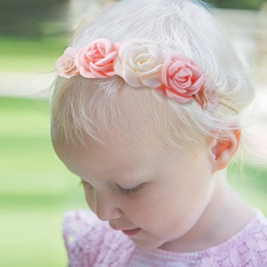 Close-up of pink and white fabric flower headband on a baby with lace leaf details