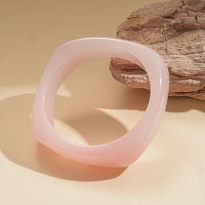 Close-up of pink resin geometric bangle set against a natural stone background