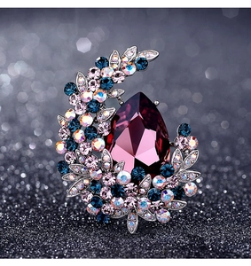 Detail of crescent moon brooch with large purple teardrop stone and colorful rhinestones