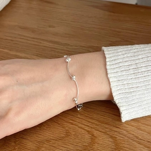 Detail of minimalist S925 sterling silver beaded bracelet on wrist with soft knit sleeve