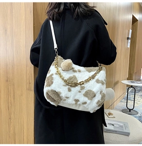 Detail view of large cow print plush tote bag with gold chain and white leather strap