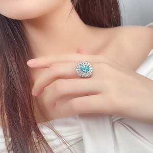 Macro shot of silver ring with oval paraiba gemstone and halo of white diamonds on hand