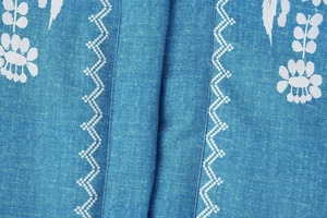 Detaillierte Stickerei auf blauem Jeansstoff mit weißen Blumen- und Zickzackmustern
