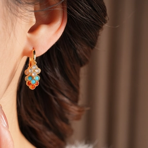 Detail of vintage gold plated cluster earrings with zircon and colorful tassels on model