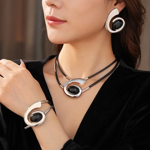 Close-up of silver spiral jewelry set with black oval stones worn by a model