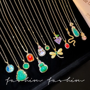 Detail of assorted gold pendant necklaces with colorful gemstones on black velvet