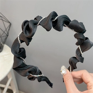 Detail of black ruffled fabric headband with hand-wound silver rhinestone chain accent