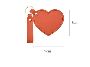 Detail showing orange PU leather heart keychain mirror with 9cm by 8cm size dimensions