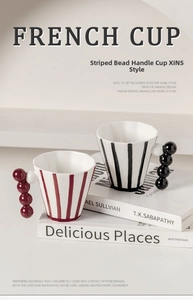 Close-up of French style striped ceramic mug with unique creative beaded handle design