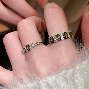 Detailed view of silver rings featuring green oval gemstones and sparkling zircon accents