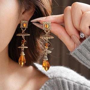 Detail of vintage bronze drop earrings with amber crystals and etched metal patterns