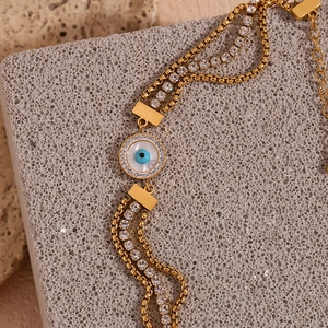 Close-up of 18K gold-plated triple chain bracelet with blue evil eye and zircon stones