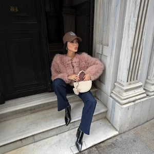 Giacca corta in pelliccia sintetica rosa con jeans blu e berretto in uno scatto street