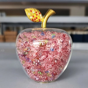 Close-up of a decorative glass apple with pink crystals and a golden leaf accent