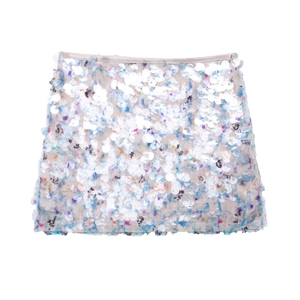 Gros plan des paillettes blanches aux reflets bleus et roses sur la mini-jupe
