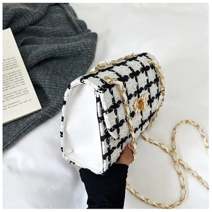 Detail of checkered tweed shoulder bag with golden chain strap and metallic swivel lock