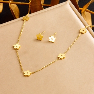 Elegant gold flower necklace and earrings jewelry set displayed on a beige gift box