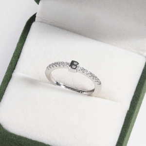 Macro view of adjustable silver letter B ring with small crystals in a green velvet jewelry box