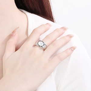 Close-up of minimalist silver stainless steel ring with white oval shell inlay on hand