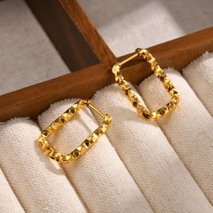 Detailed close-up of gold-plated rectangular earrings with diamond-patterned textures