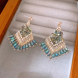 Elegant gold earrings with blue crystal teardrop tassels and pearls on a velvet box