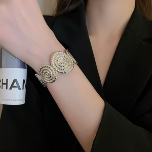 Close-up of a silver spiral textured open bangle on a model wearing a black blazer