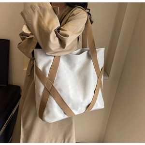 Detailed shoulder view of a large capacity cream canvas tote bag with brown woven straps