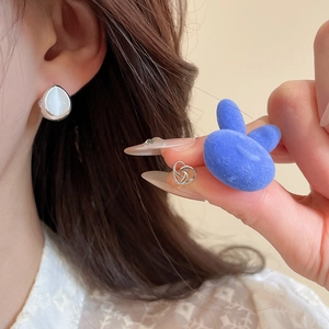 Detailed shot of silver water-drop earrings with white opal and hollow heart studs