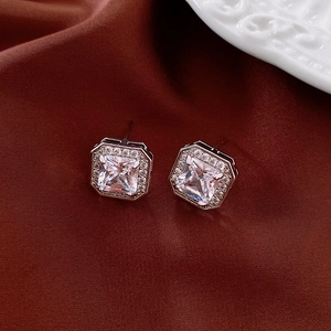 Détail de boucles d'oreilles carrées en zircon argenté sur fond de soie rouge foncé