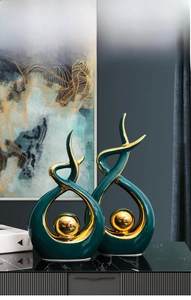 Detail of luxury green ceramic statues with gold accents on marble tabletop