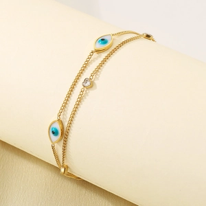 Detail showing double-layer golden chain anklet with blue evil eye charms and heart zircon
